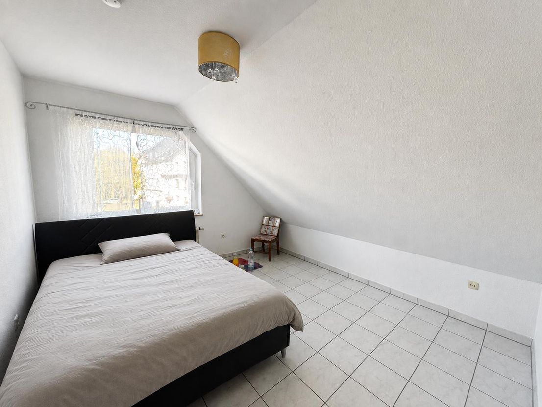 Zweites Schlafzimmer mit Doppelbett unter der Dachschräge und Fenster zur ruhigen Seite