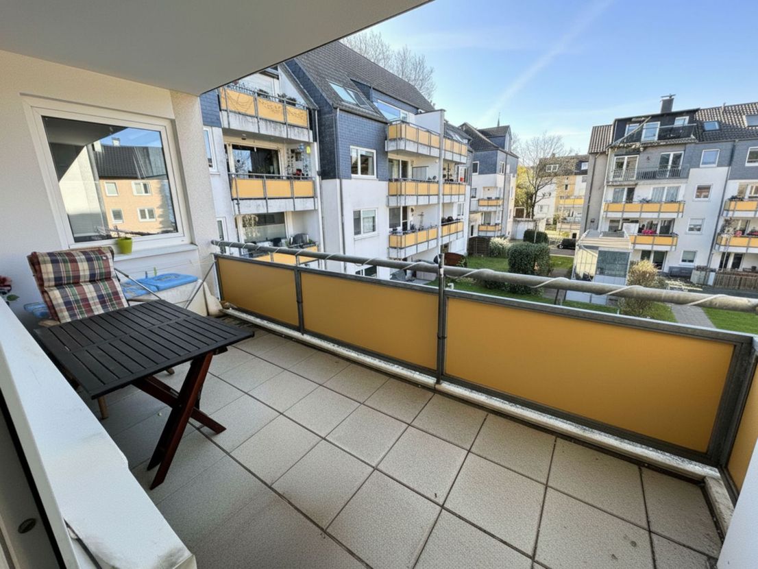 Balkon der Wohnung mit Tisch und Stuhl, Blick in den ruhigen Innenhof- und Gartenbereich