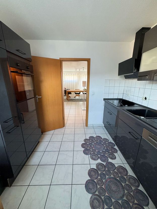 Separate Küche mit dunkler Einbauküche, Backofen und Blick in den Essbereich