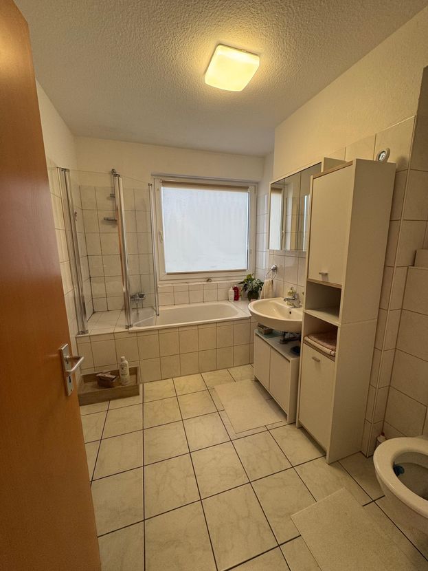 Tageslichtbad mit Badewanne, Duschabtrennung, Waschbecken und Fenster